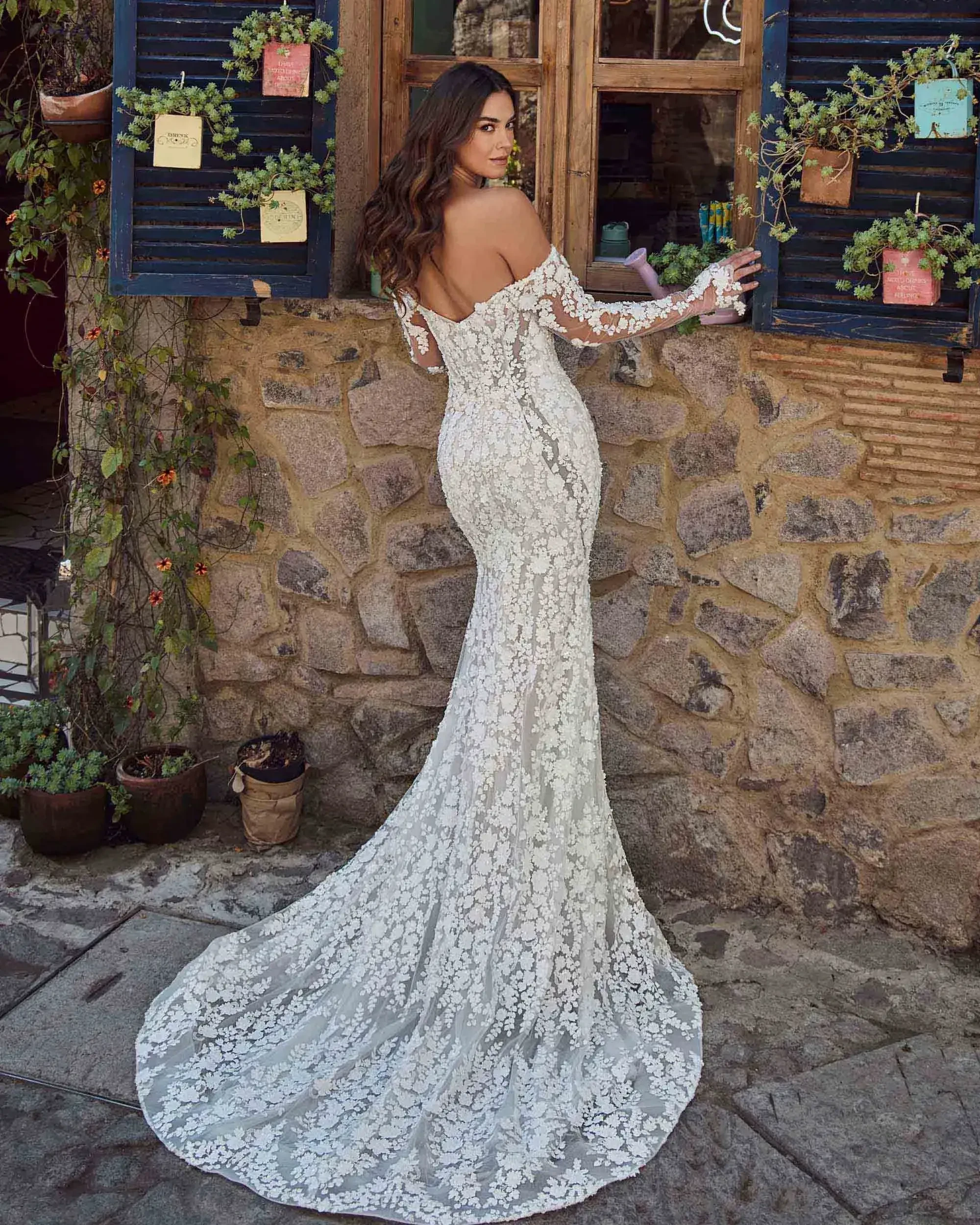 model is wearing a long sleeve off the shoulder fit and flare wedding dress