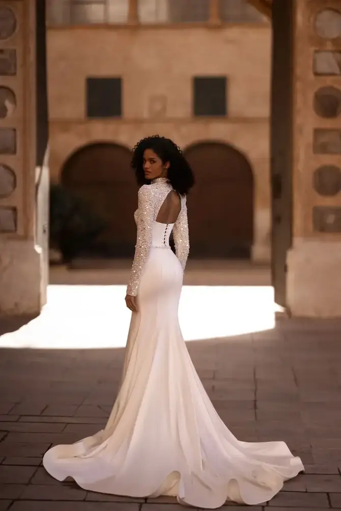 model is wearing a strapless fit and flare wedding dress with a bridal jacket