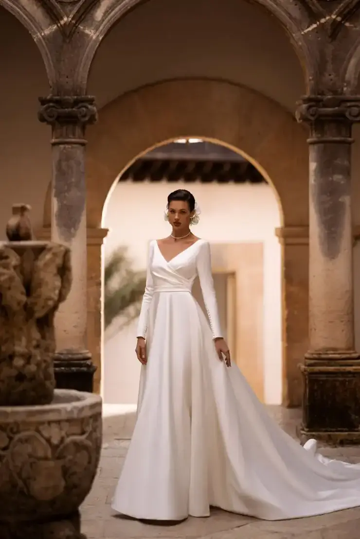 model is wearing a long sleeve a-line wedding dress with a plunging neckline
