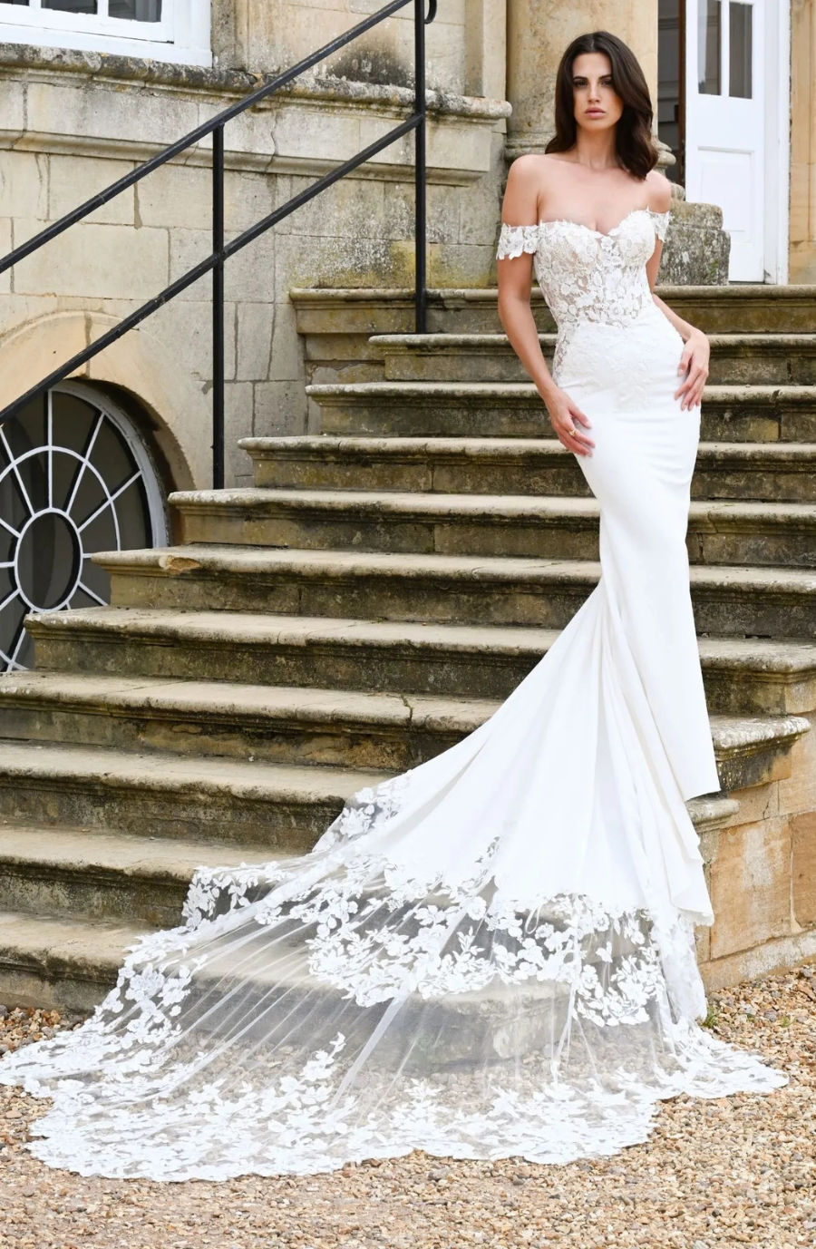 model is wearing an off the shoulder fitted lace wedding dress