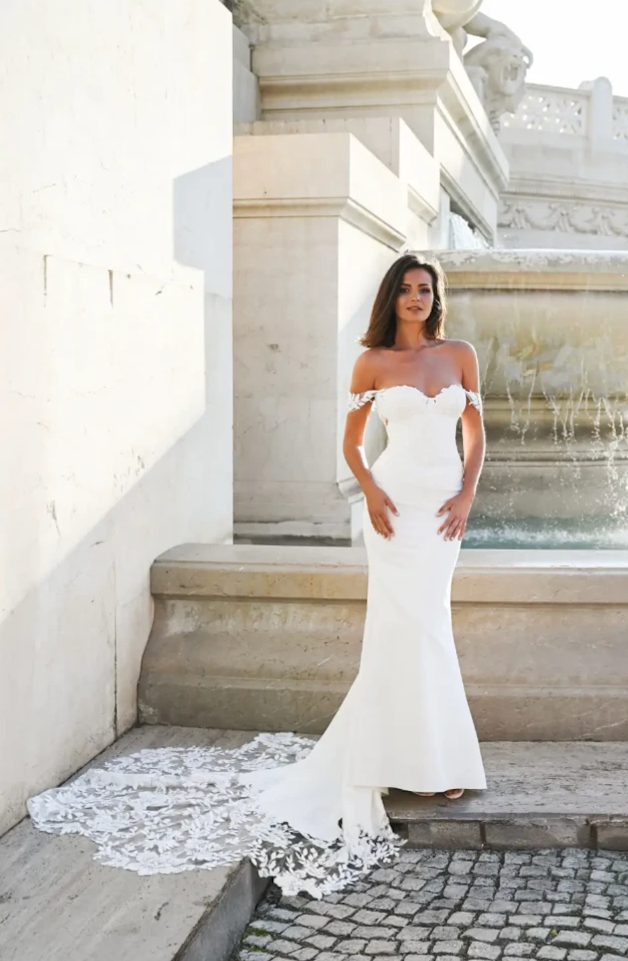 model is wearing a sleek off the shoulder wedding dress