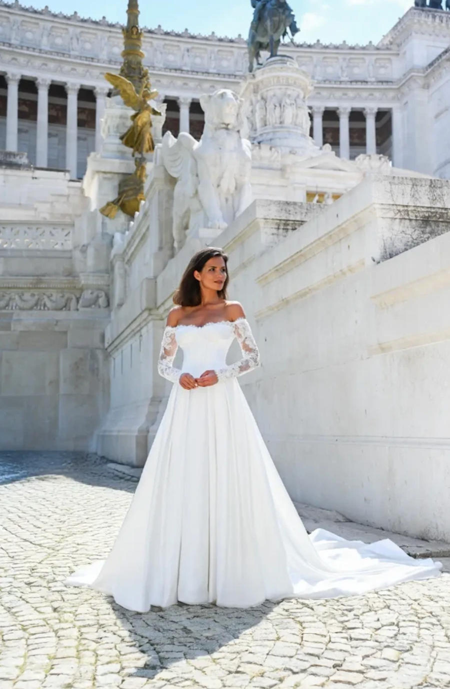 model is wearing an off the shoulder long sleeve wedding dress